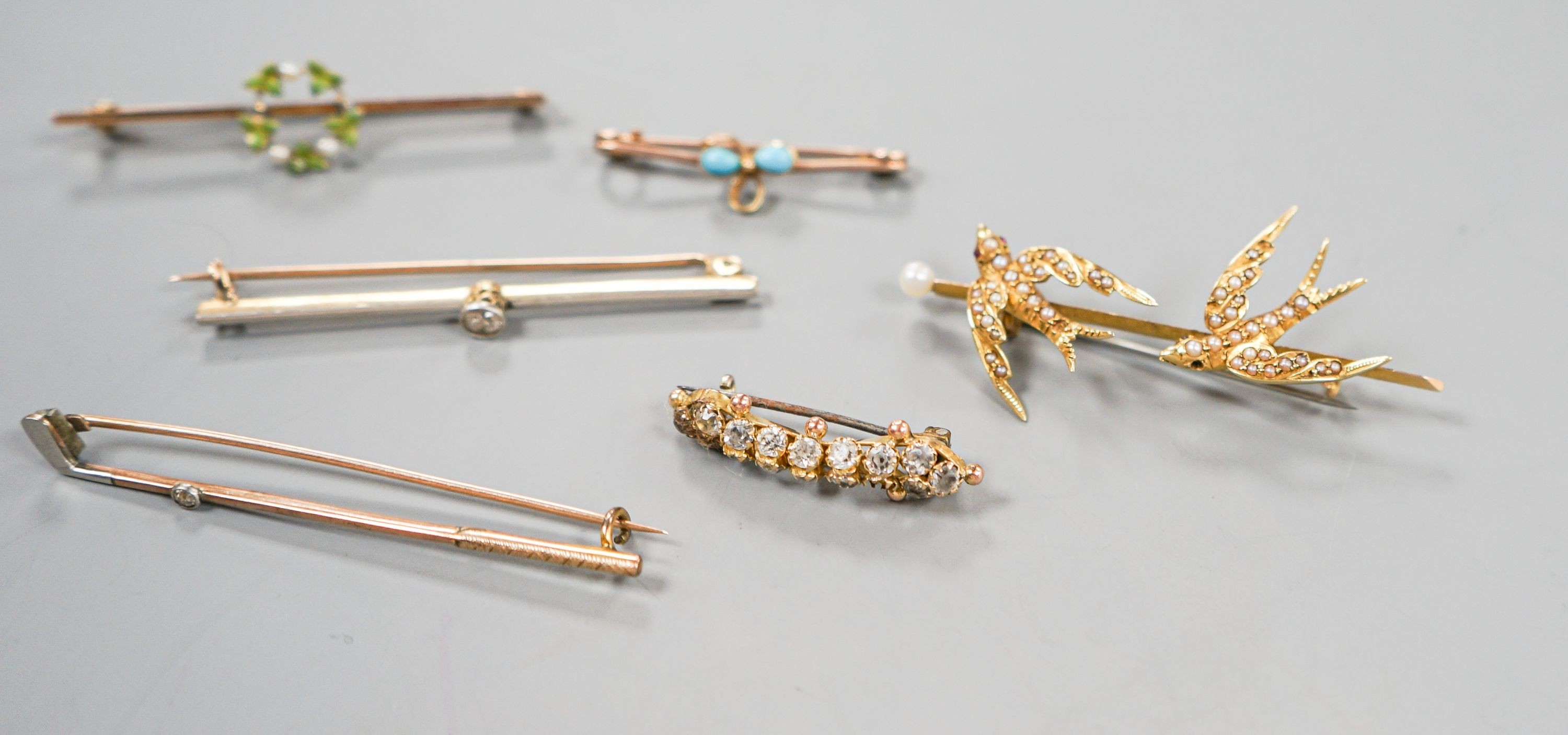 A collection of six assorted yellow metal bar brooches, including seed pearl set twin swallow, diamond set gold club and solitaire diamond set
